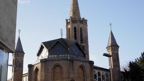 a close-up view of a historic church in cologne, featuring its tall spires and intricate architecture, framed by a modern building on a bright day