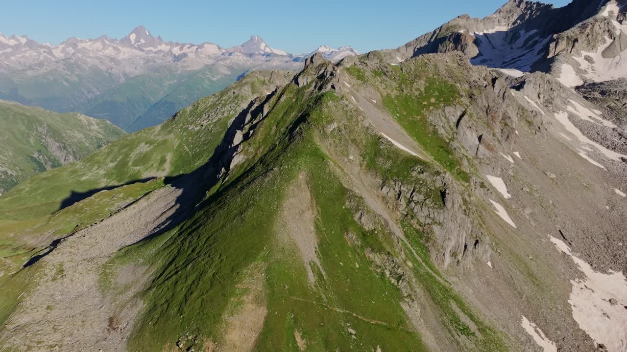 Drone climbs steadily over alpine ridge, steep slopes and glacier lines, Valais