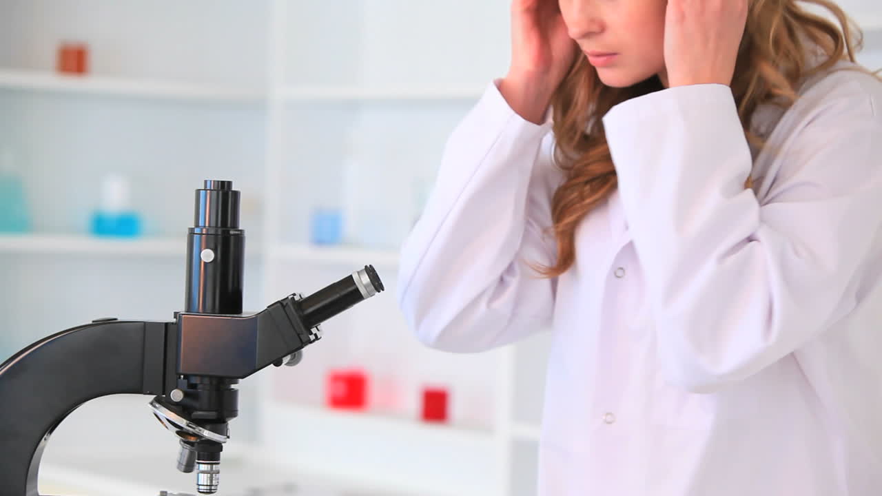 mujer joven mirando a través de un microscopio