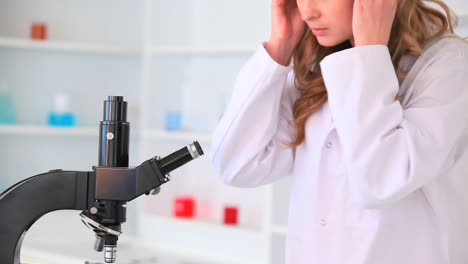 mujer joven mirando a través de un microscopio