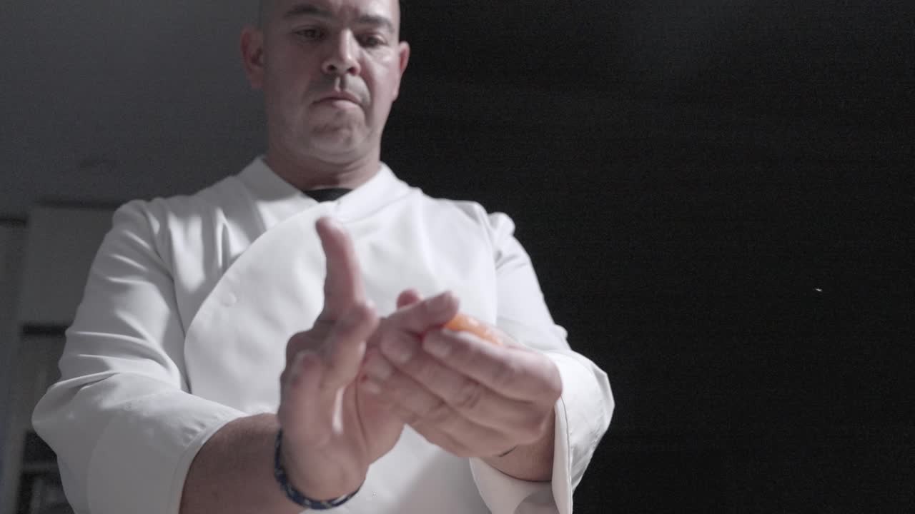 A low angle static shot of a sushi chef preparing, packing, and making sushi rolls. for showcasing sushi preparation, culinary techniques, and the artistry of sushi making in a professional kitchen.
