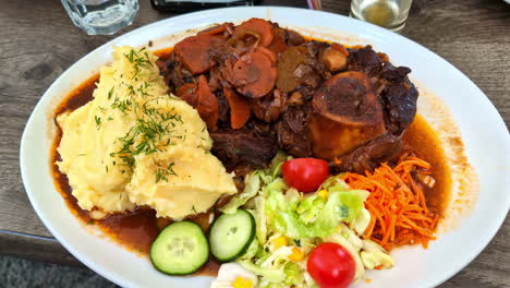 Huge-portion-of-meat-and-mashed-potatoes-served-in-restaurant,-close-up