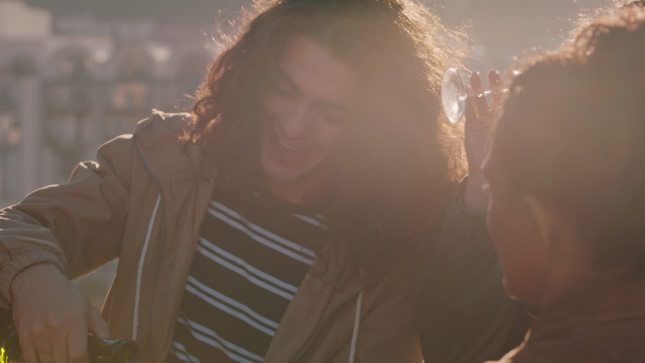 술을 마시는 옥상 파티를 축하하는 다양한 친구들, 일몰 때 동창회 축하를 즐기는 젊은 남자가 샴페인을 붓는 모습