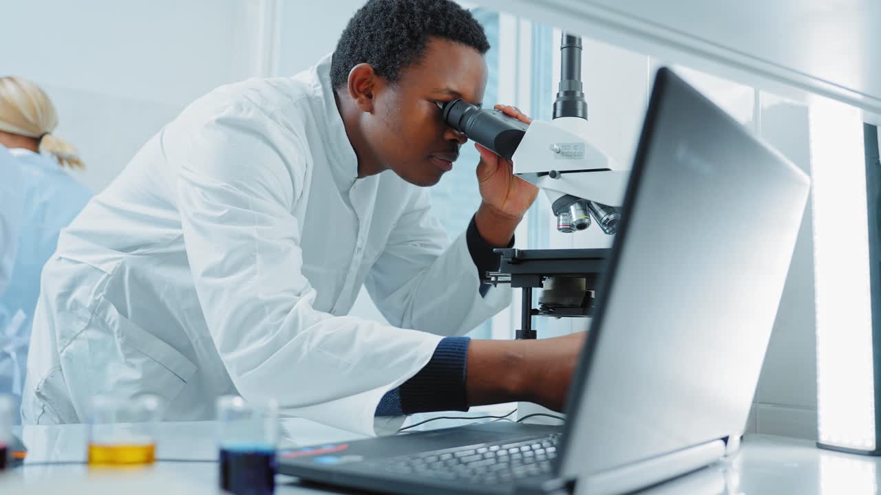 Scientist working with microscope and laptop in a laboratory