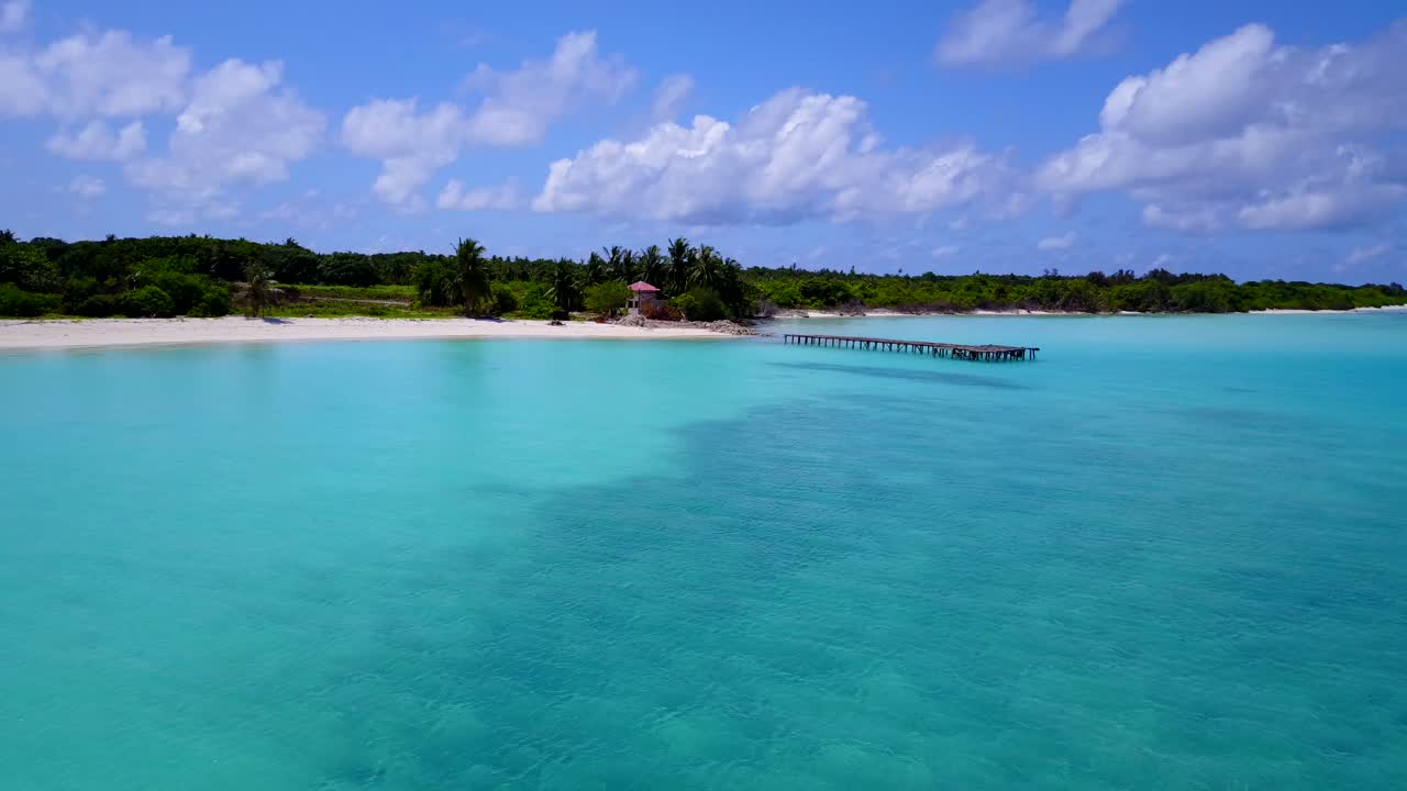 volando sobre una isla tropical cubierta de palmeras rodeada de mar turquesa a baja altura