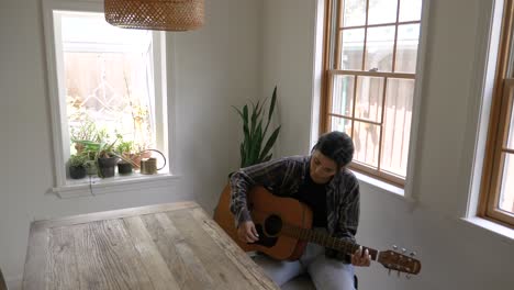 teenage puerto rican female practicing playing acoustic guitar in clean modern home interior