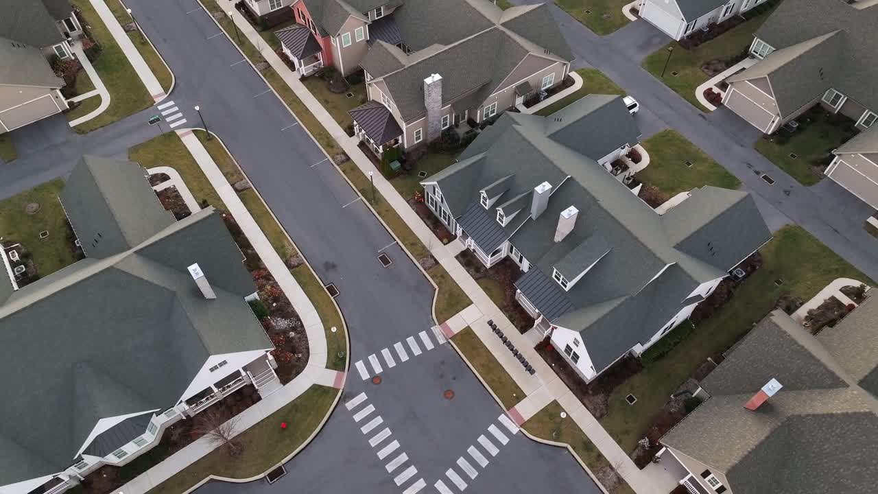 New build two-story houses with grey roof and white facade in luxury housing area of America.Aerial top down Landing shot. High class residential area during sunset time.