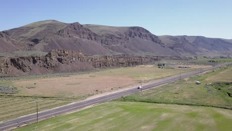 Aerial-tracks-white-van-driving-in-scenic-scablands-coulee-bottom