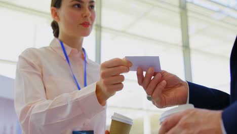 caucasian businesswoman giving a visit card to a businessman in the office lobby 4k