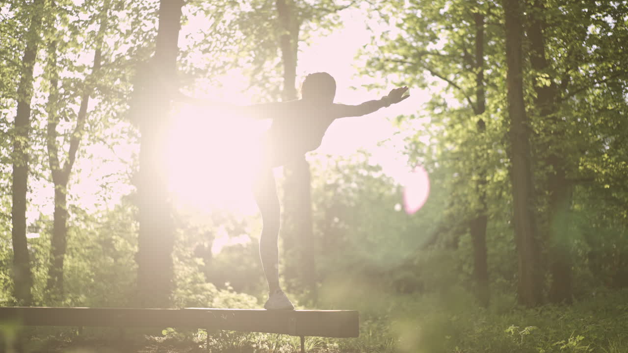 Woman doing yoga on a wooden beam in nature