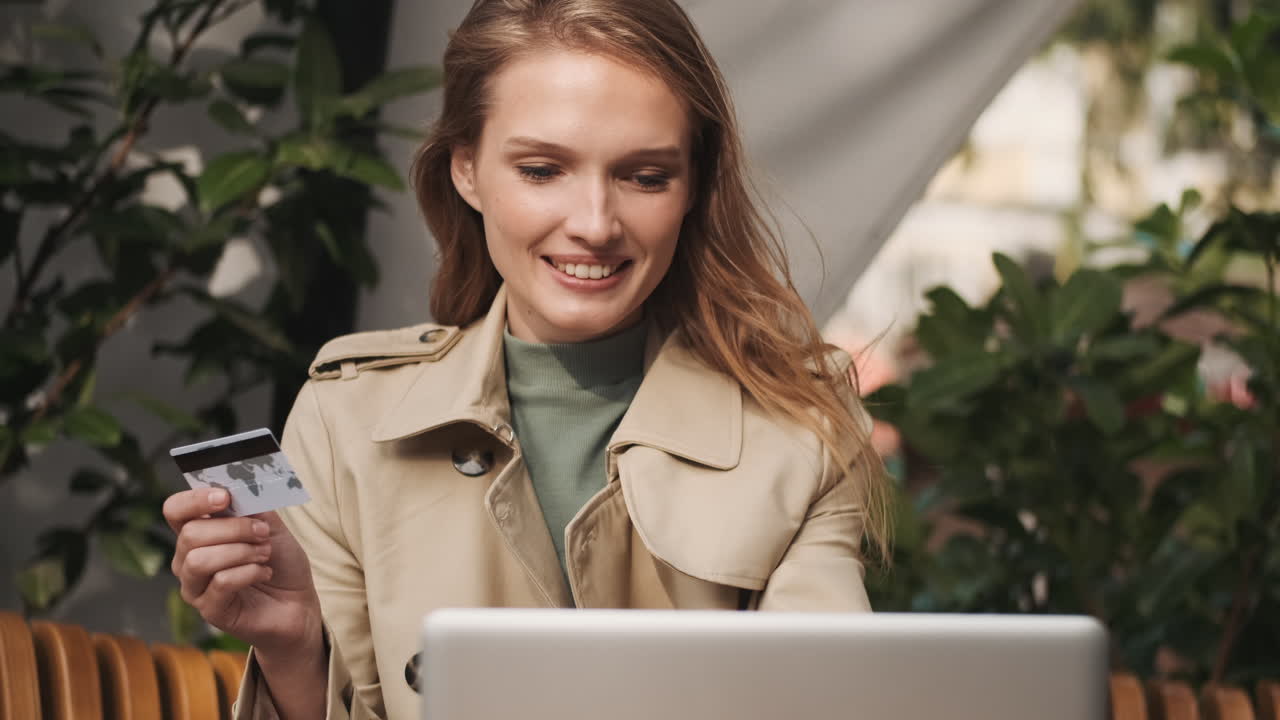 Caucasian female student online shopping on laptop outdoors.