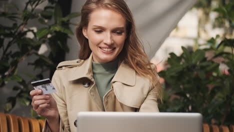 caucasian female student online shopping on laptop outdoors.