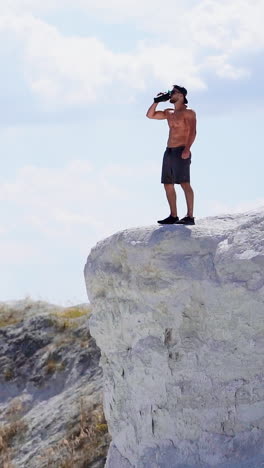 man standing on top of mountain. young sportive man standing on top of cliff vertical video