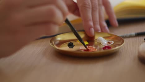 Close-up-of-female-hand-mixing-paints-with-paintbrush