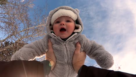 POV-Slo-Mo-Aufnahme-Eines-Süßen,-Glücklichen-Kindes-In-Einem-Warmen,-Flauschigen-Mantel,-Das-In-Die-Luft-Gehoben-Wird