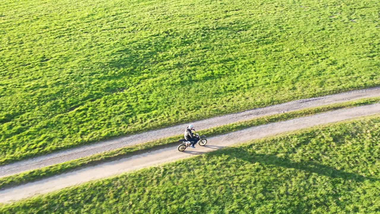 Person Riding Dirt Bike on a Path Through Green Field
