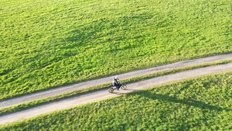 person riding dirt bike on a path through green field
