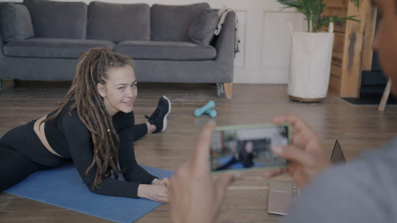 Woman stretching and taking a video of her workout session in the living room.