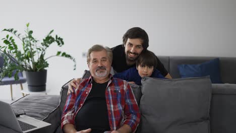 Portrait-of-happy-caucasian-three-generation-men-smiling-to-the-camera-at-home