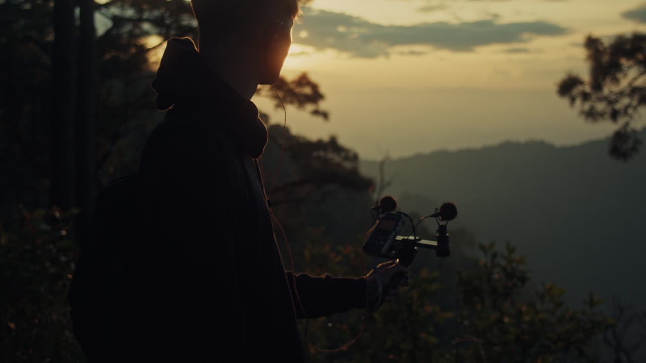Vlogger recording sunset views from mountaintop
