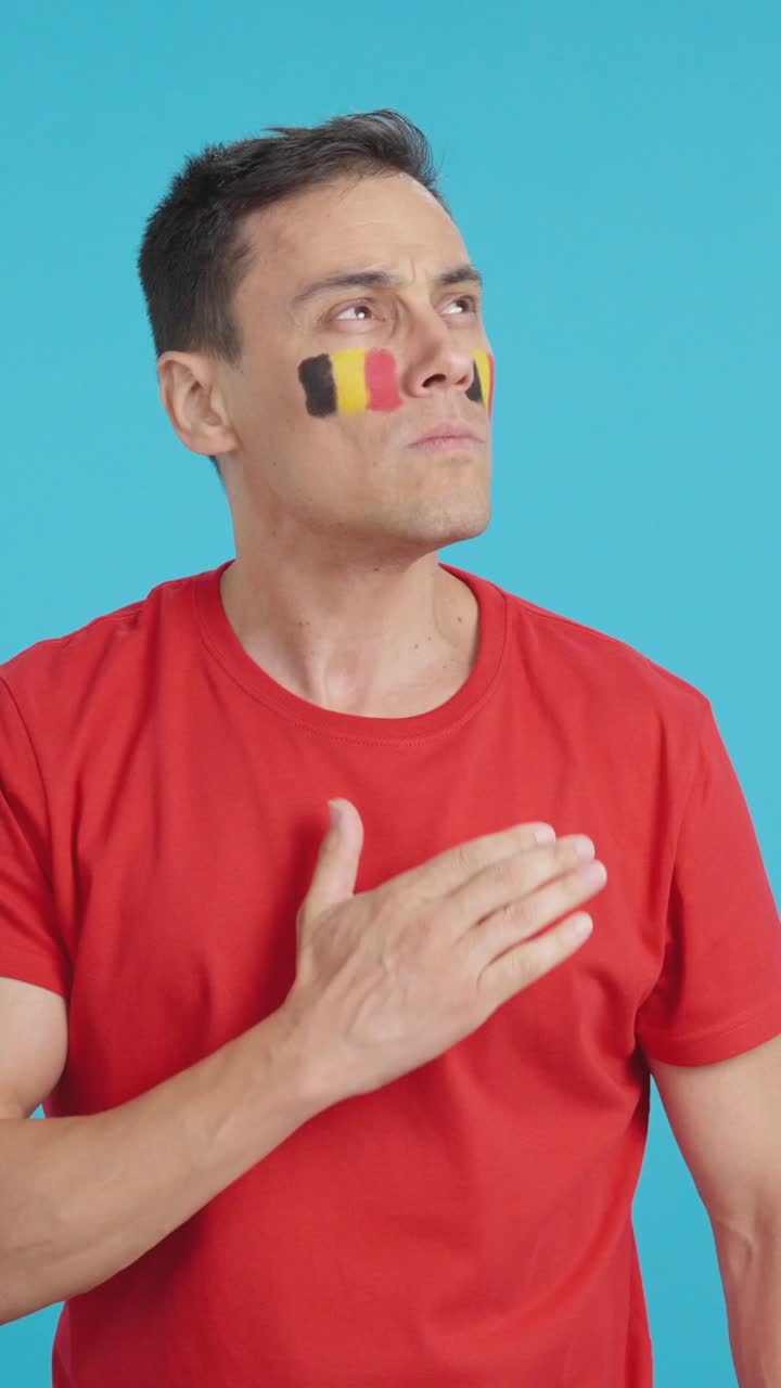 Man listening to the Belgium national anthem with solemnity