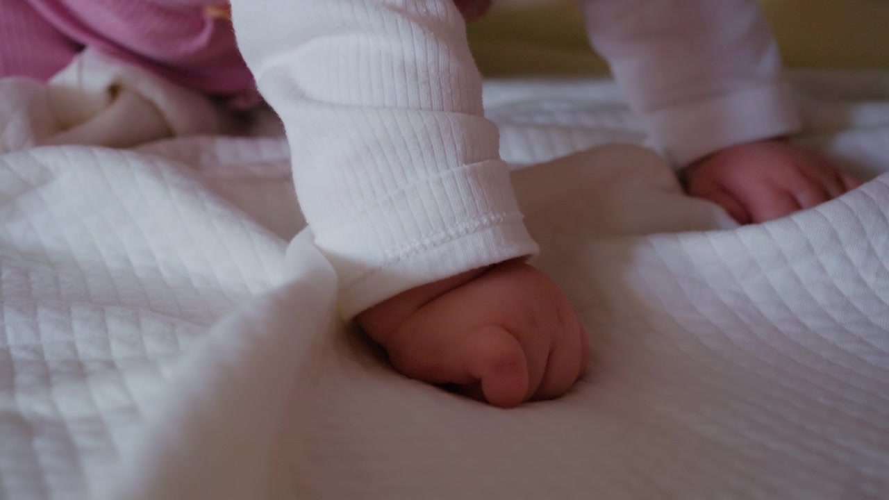 Scatto macro della manina di un neonato appoggiata su una coperta dalla trama