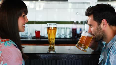 una pareja feliz interactuando mientras beben cerveza.