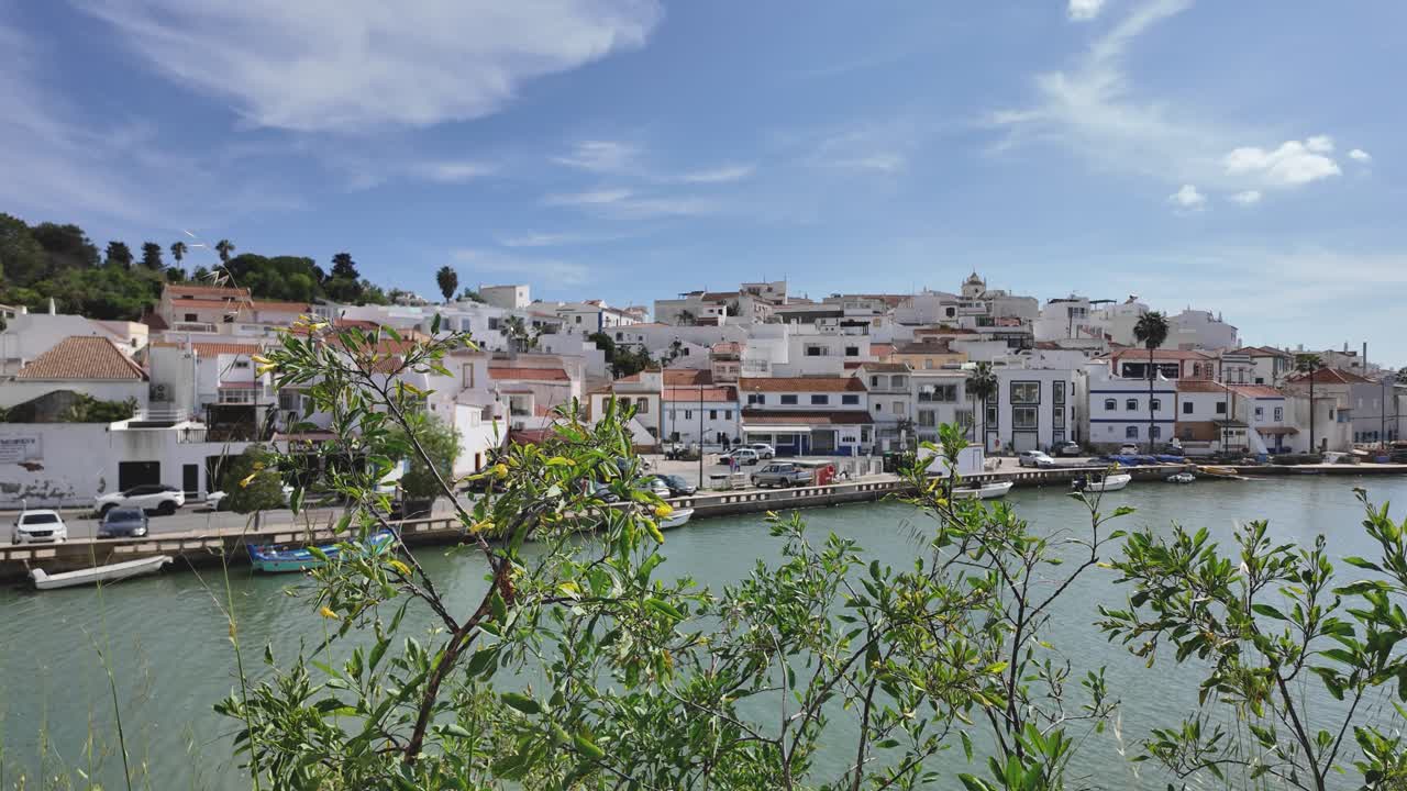 Ferragudo village in Portugal with white houses along the riverside under a bright sky