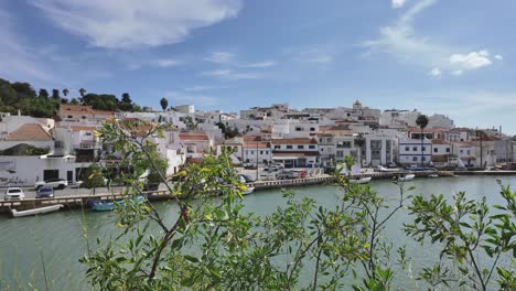 ferragudo village in portugal with white houses along the riverside under a bright sky
