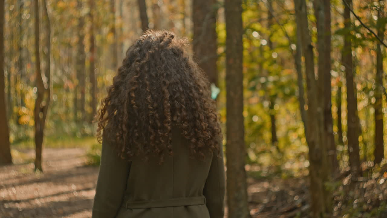 Woman with Curly Hair Walking in Autumn Forest