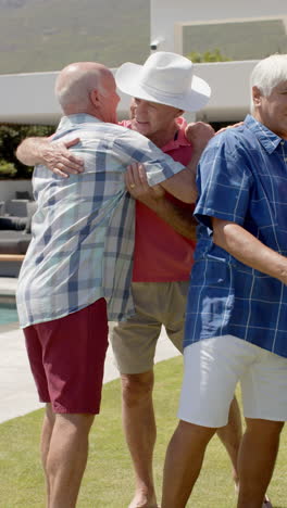 happy senior diverse men talking and embracing in garden in slow motion