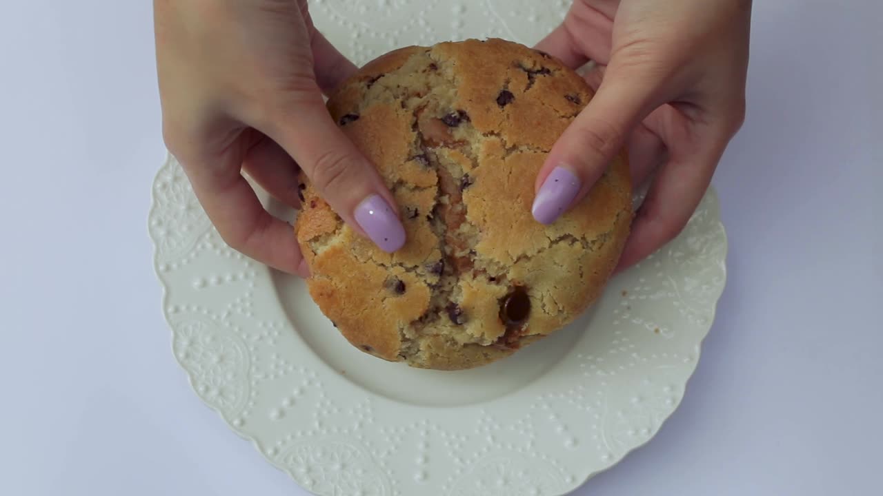 둘세 데 레체 - 밀크 캔디로 가득 찬 거대한 초콜릿 칩 쿠키를 부수는 여성 손