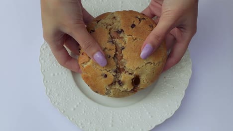 Female-hands-breaking-a-huge-chocolate-chip-cookie-filled-with-dulce-de-leche---milk-candy