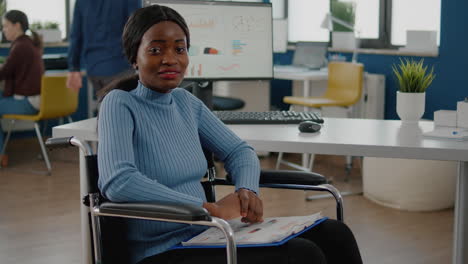 African-woman-employee-looking-at-camera-smiling-sitting-in-wheelchair