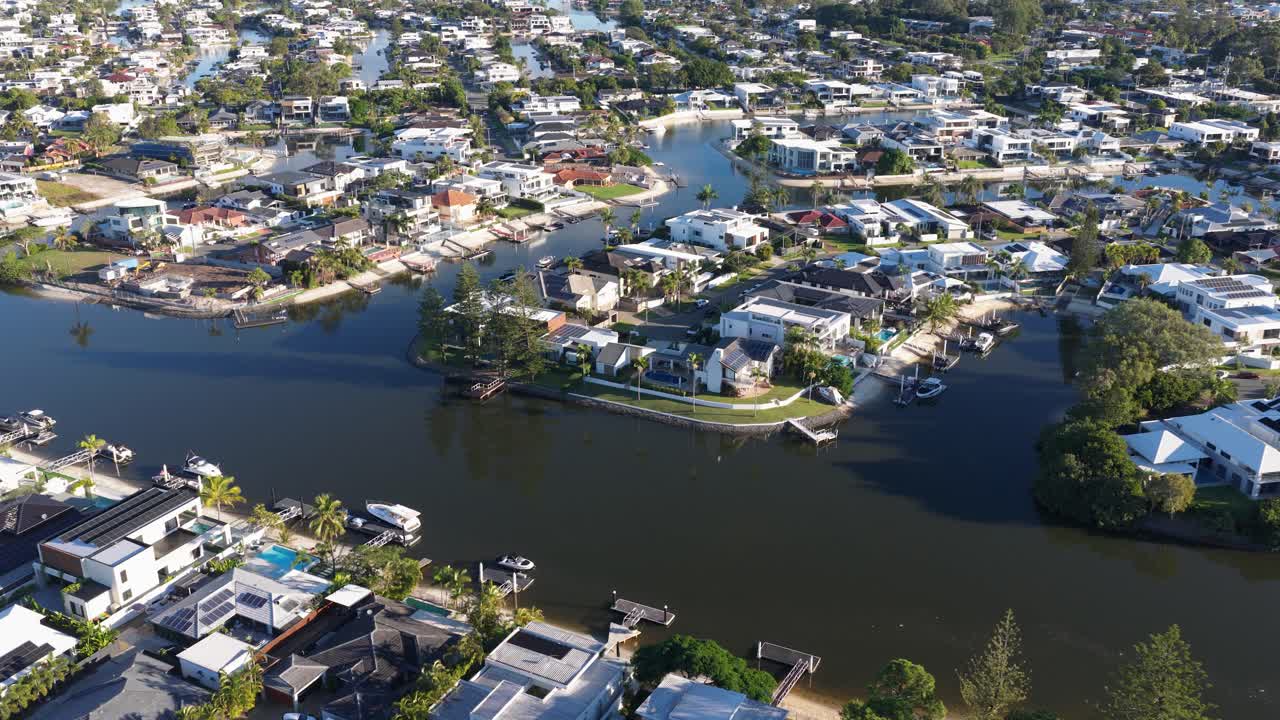 Aerial footage captures scenic waterfront homes in Gold Coast, Australia, under bright daylight with clear skies and calm waters