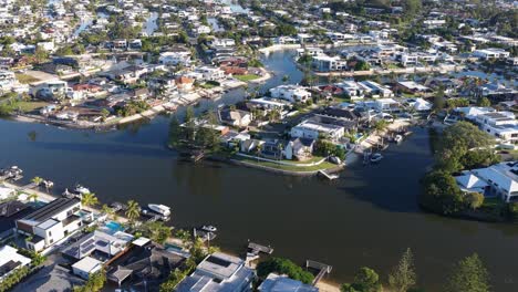aerial footage captures scenic waterfront homes in gold coast, australia, under bright daylight with clear skies and calm waters