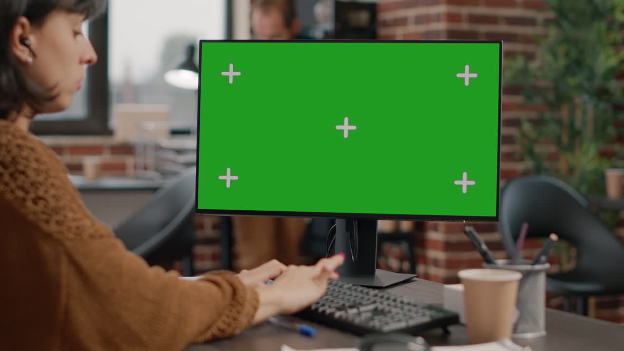 Woman working at computer with green screen monitor