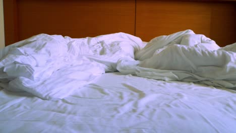 panning shot of messy hotel bed after great night