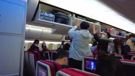 chinese people inside aircraft removing hand luggage in cabin beijing capital airport during covid-19 pandemic