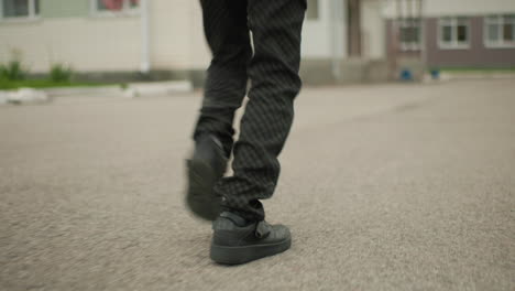 lower angle view of kid in black pant running forward towards steps with iron frame showing determined movement focus on legs in motion creating dynamic perspective of student heading to school