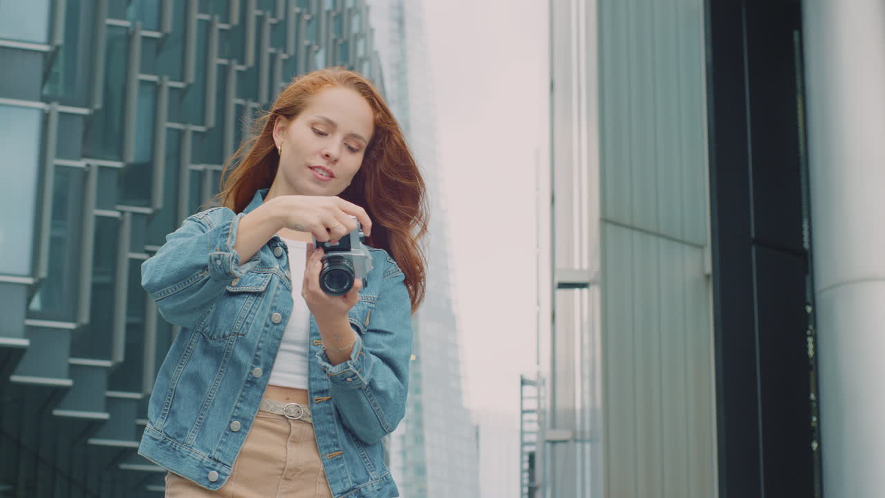 도시 에 있는 젊은 여성 이 소셜 미디어 에 게시 하기 위해 디지털 카메라 로 사진 을 찍고 있다