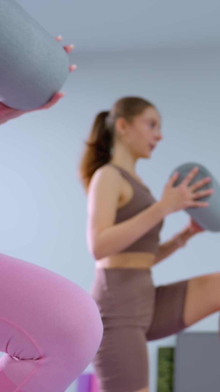 две женщины занимаются фитнес-упражнениями, держа в руках пенные ролики в современной комнате в городском стиле с минималистским декором, тренировка подчеркивает баланс, координацию и силовую тренировку