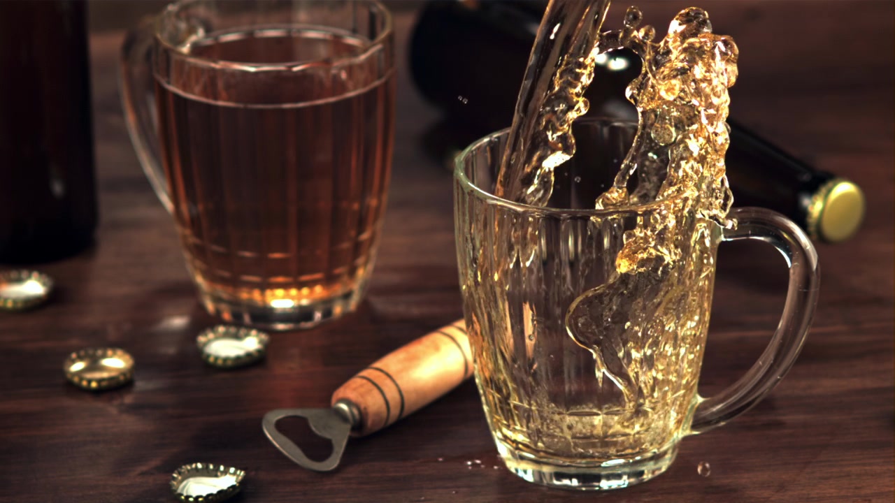 Cerveja Dourada Sendo Derramada em Câmera Lenta em uma Caneca de Vidro sobre uma Mesa de Madeira