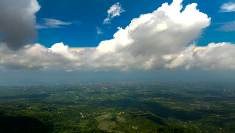 hyperlapse timelapse of abstract white clouds moving in blue sky over bali verdant landscape, indonesia