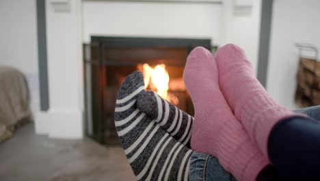 Pies-De-Pareja-En-Calcetines-Relajándose-En-Casa-Frente-Al-Fuego-Abierto,-Cámara-Lenta