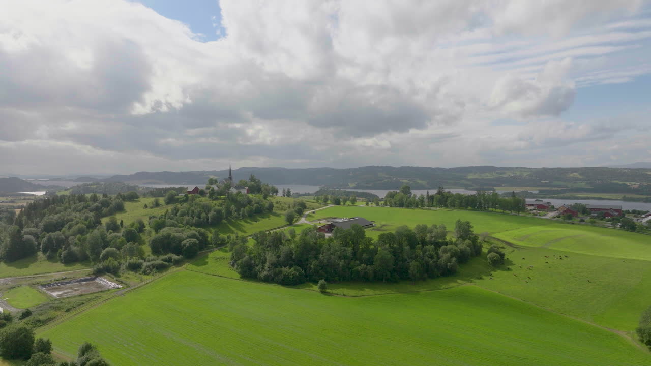 hermoso paisaje de granja con iglesia distante en la cima de una colina en un día soleado