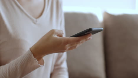 mujer usando un teléfono inteligente en un sofá