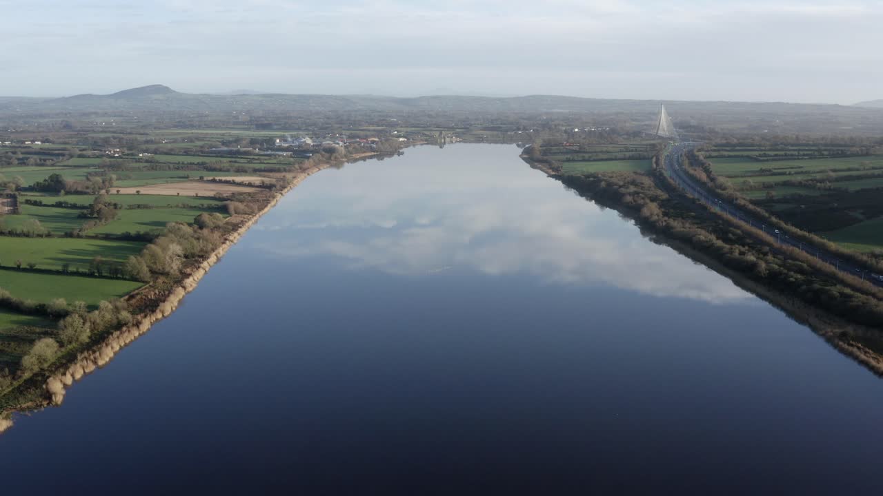 공중: 유리처럼 매끄러운 강은 하늘과 구름, 먼 다리를 반영합니다.