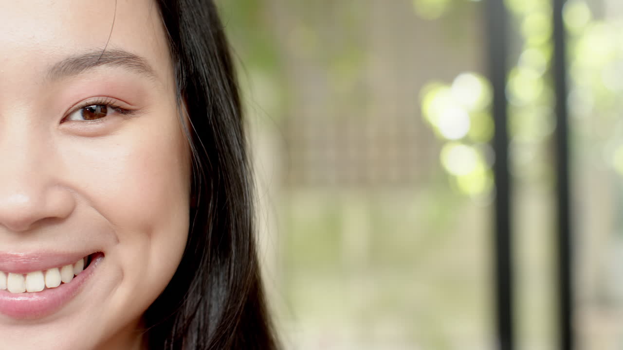 Smiling woman with long hair showing dimples, close-up portrait outdoors, copy space