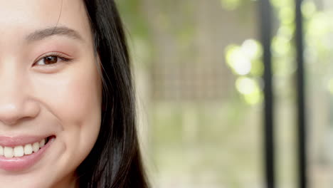 smiling woman with long hair showing dimples, close-up portrait outdoors, copy space